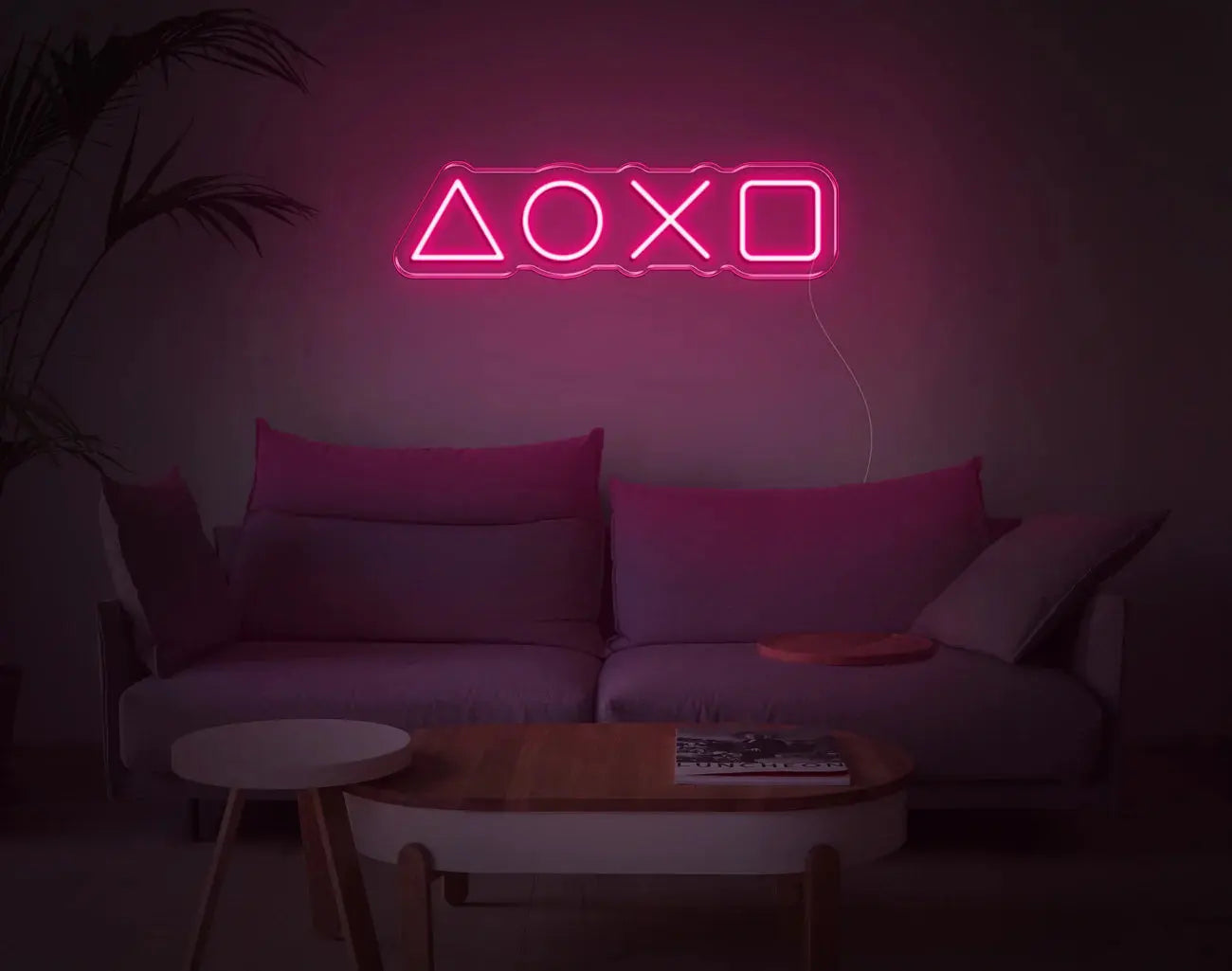 Enseigne gaming LED néon rose vif PlayStation au-dessus d’un canapé