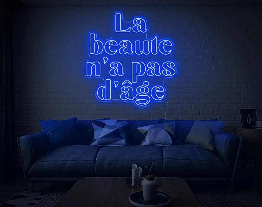 Enseigne LED néon DIY bleue La beauté n’a pas d’âge lumineuse au-dessus d’un canapé moderne
