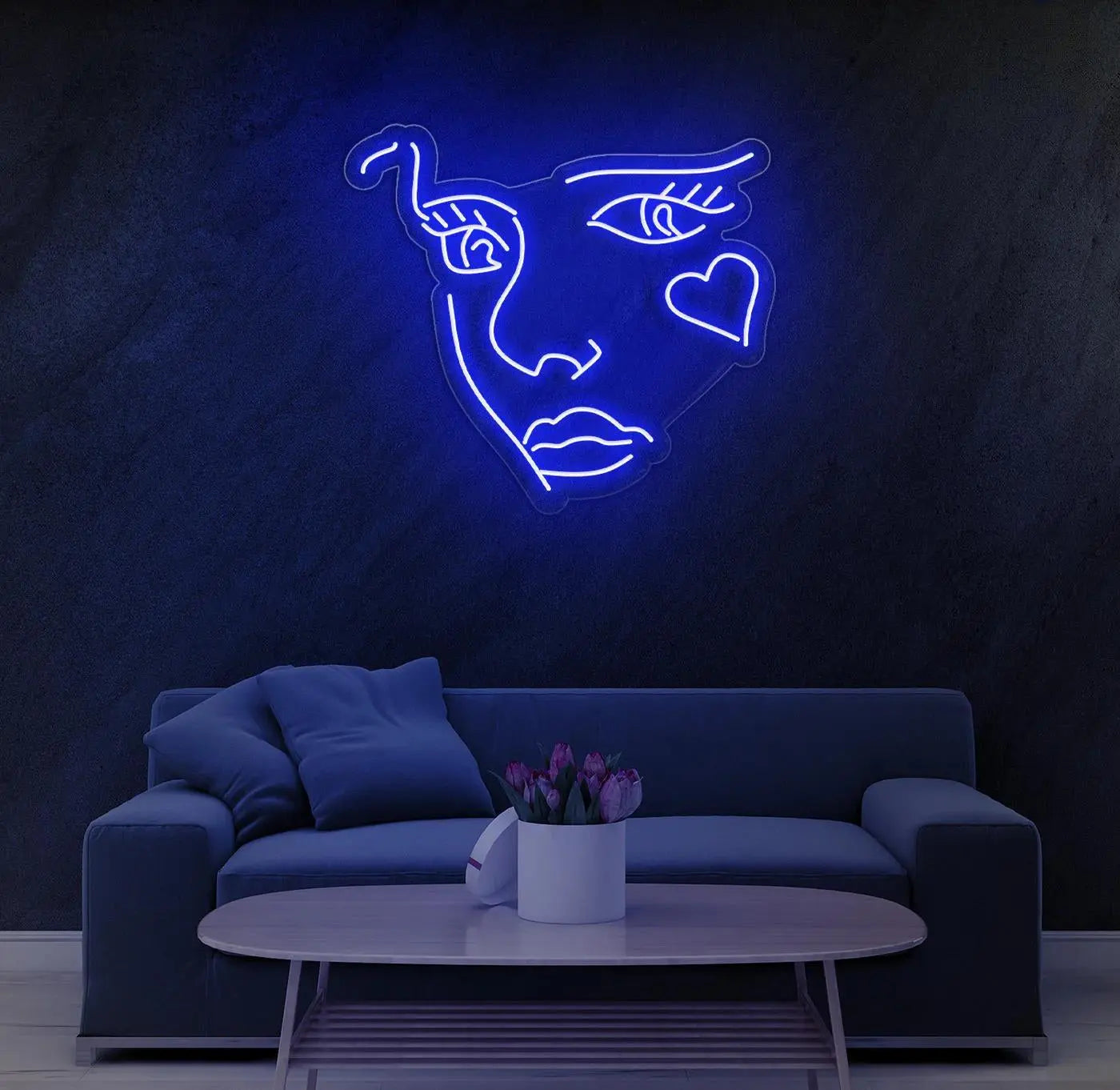 Néon LED visage abstrait bleu installé au mur au dessus d’un canapé moderne dans un salon minimaliste.