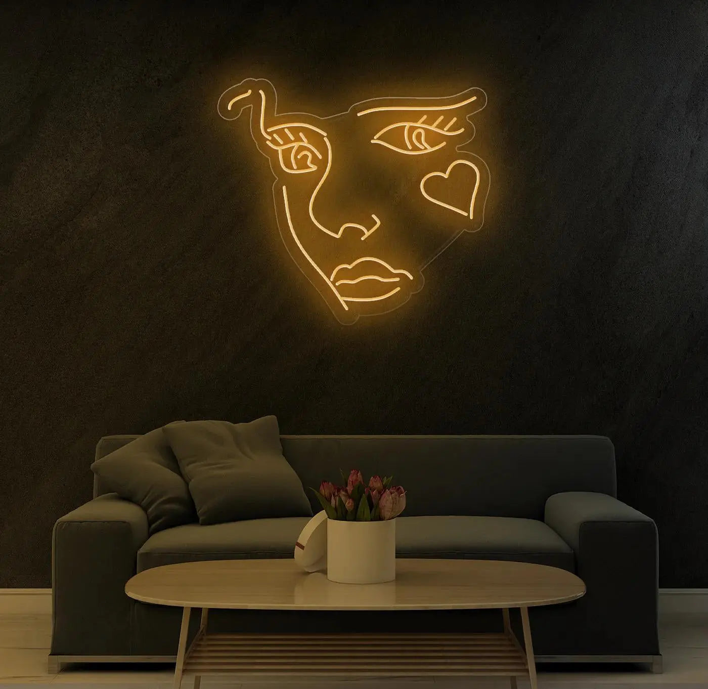 Enseigne néon LED visage abstrait jaune chaud éclairant un mur de salon contemporain au dessus d’un canapé.