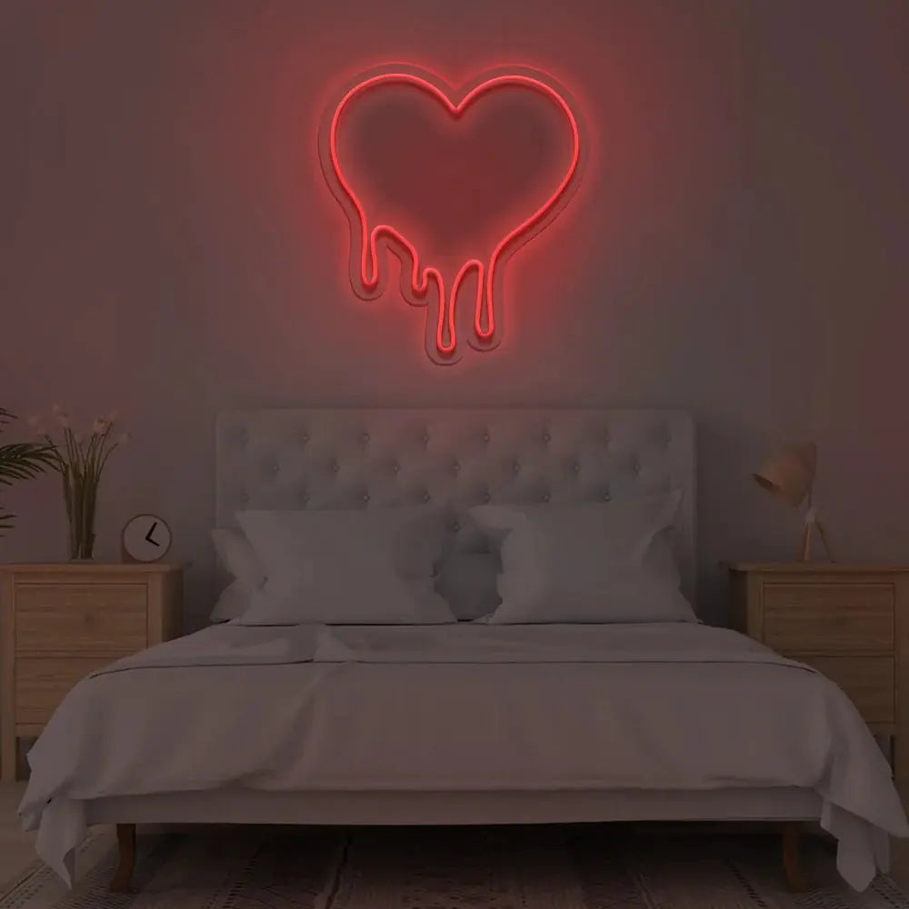 Néon cœur fondant rouge installé au-dessus d’un lit pour ambiance romantique