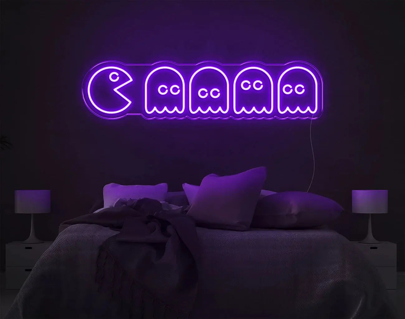 Enseigne LED néon Pacman violette utilisée comme décoration murale rétro au-dessus d’un lit.