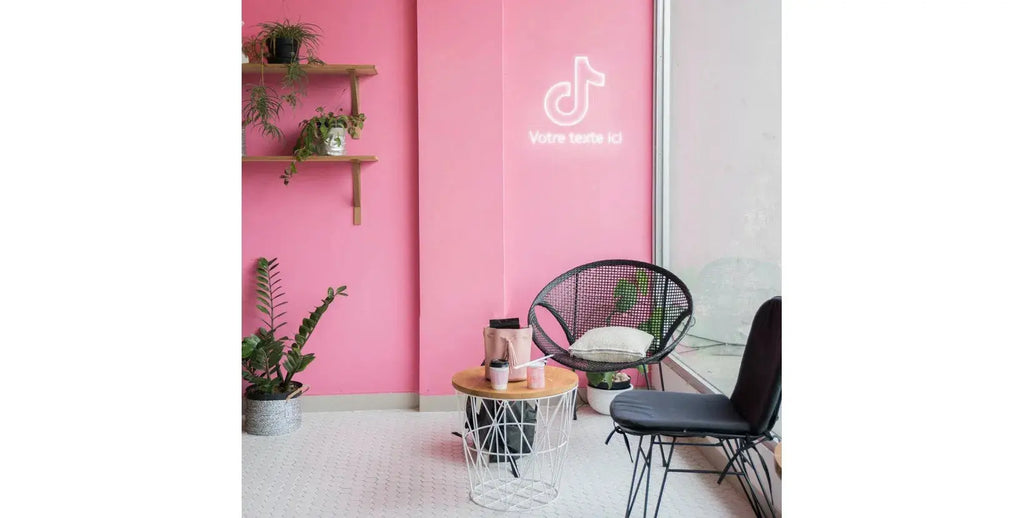 Enseigne néon LED style TikTok projetée sur un mur rose avec mobilier lounge moderne, décoration lumineuse néon DIY.